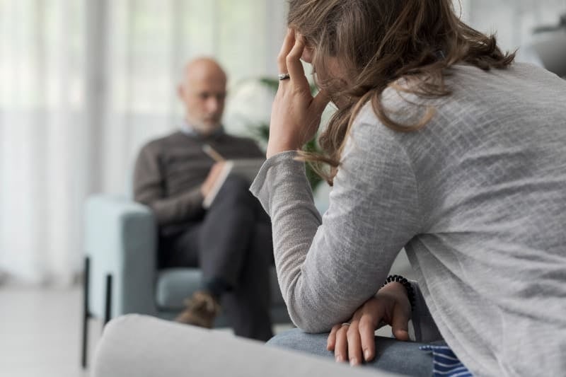 psicologo fazendo anotaçoes enquanto ouve uma paciente