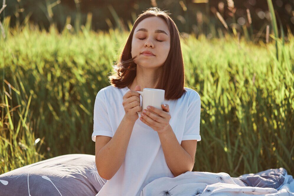 mulher-relaxada-posando-ao-ar-livre-com-uma-xicara-de-cha