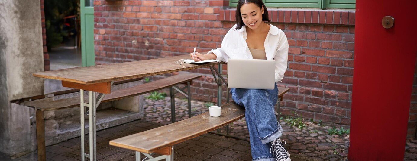 jovem-estudando-no-laptop-sentada-em-um-cafe-ao-ar-livre