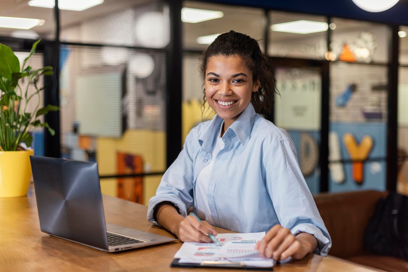 mulher-sorridente-trabalhando-com-laptop-e-papeis-no-escritorio