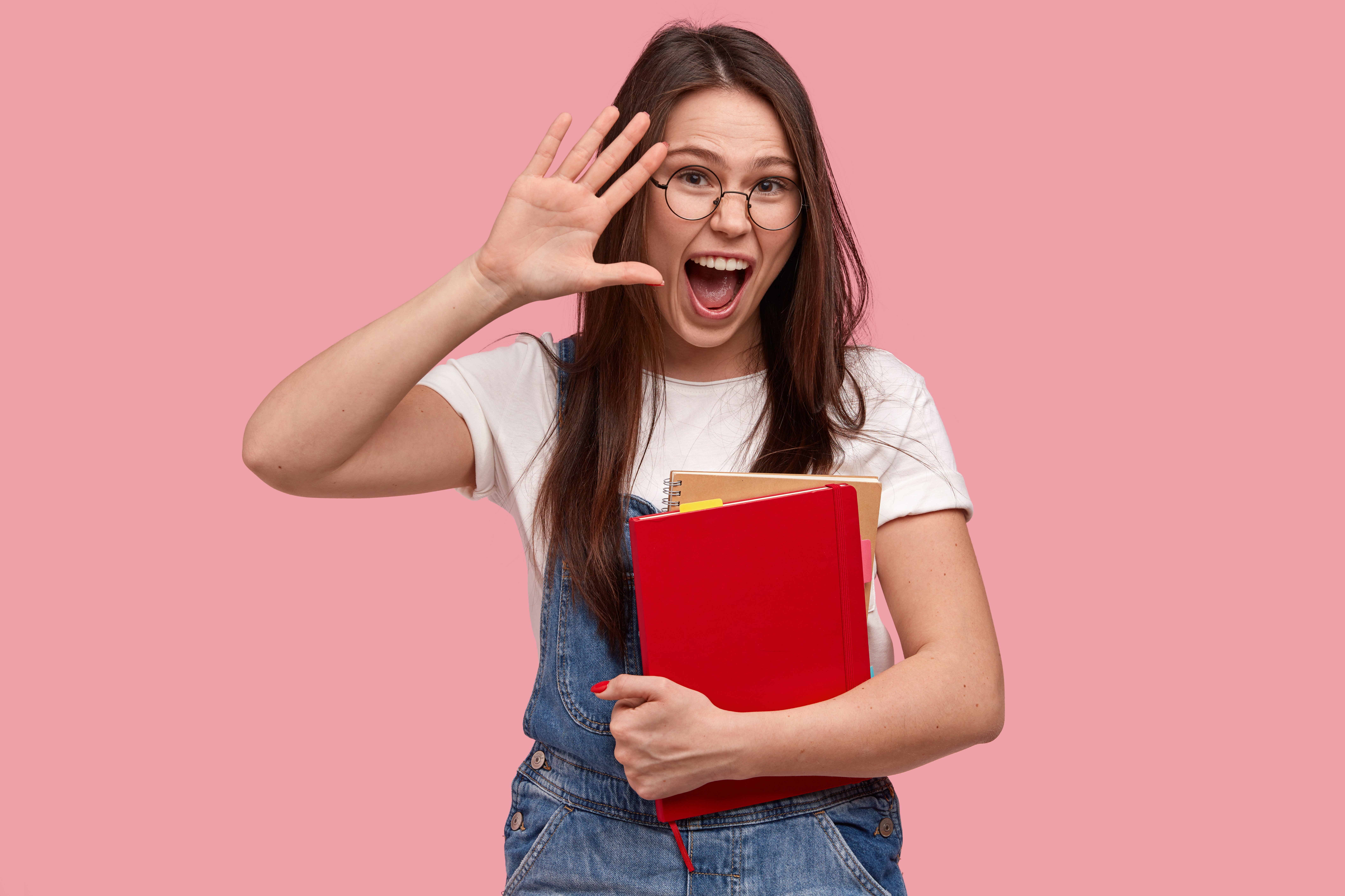 jovem morena de macação jeans segurando cadernos