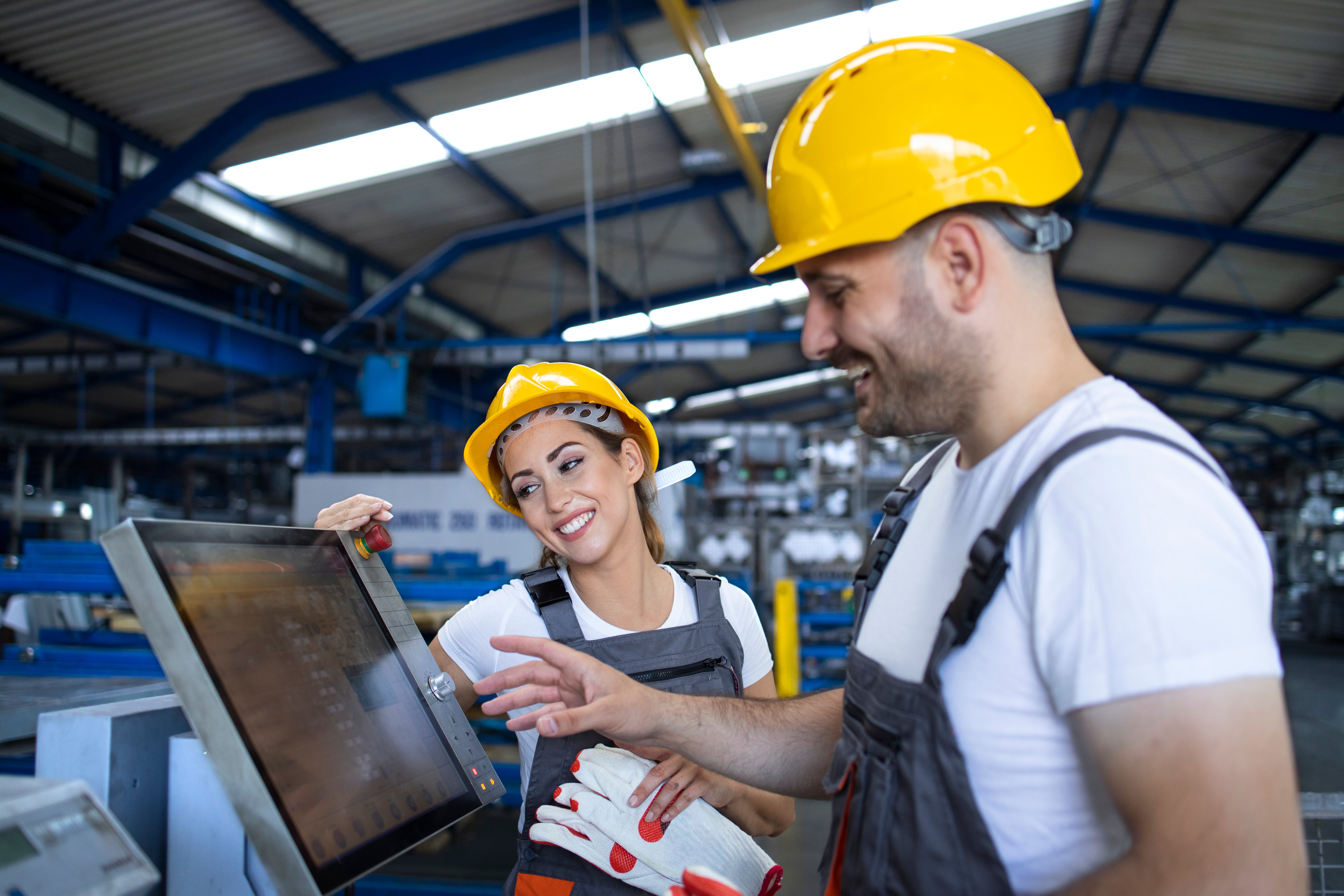 dois profissionais de engenharia de produção analisando um relatório digital dentro de uma fabrica de produção